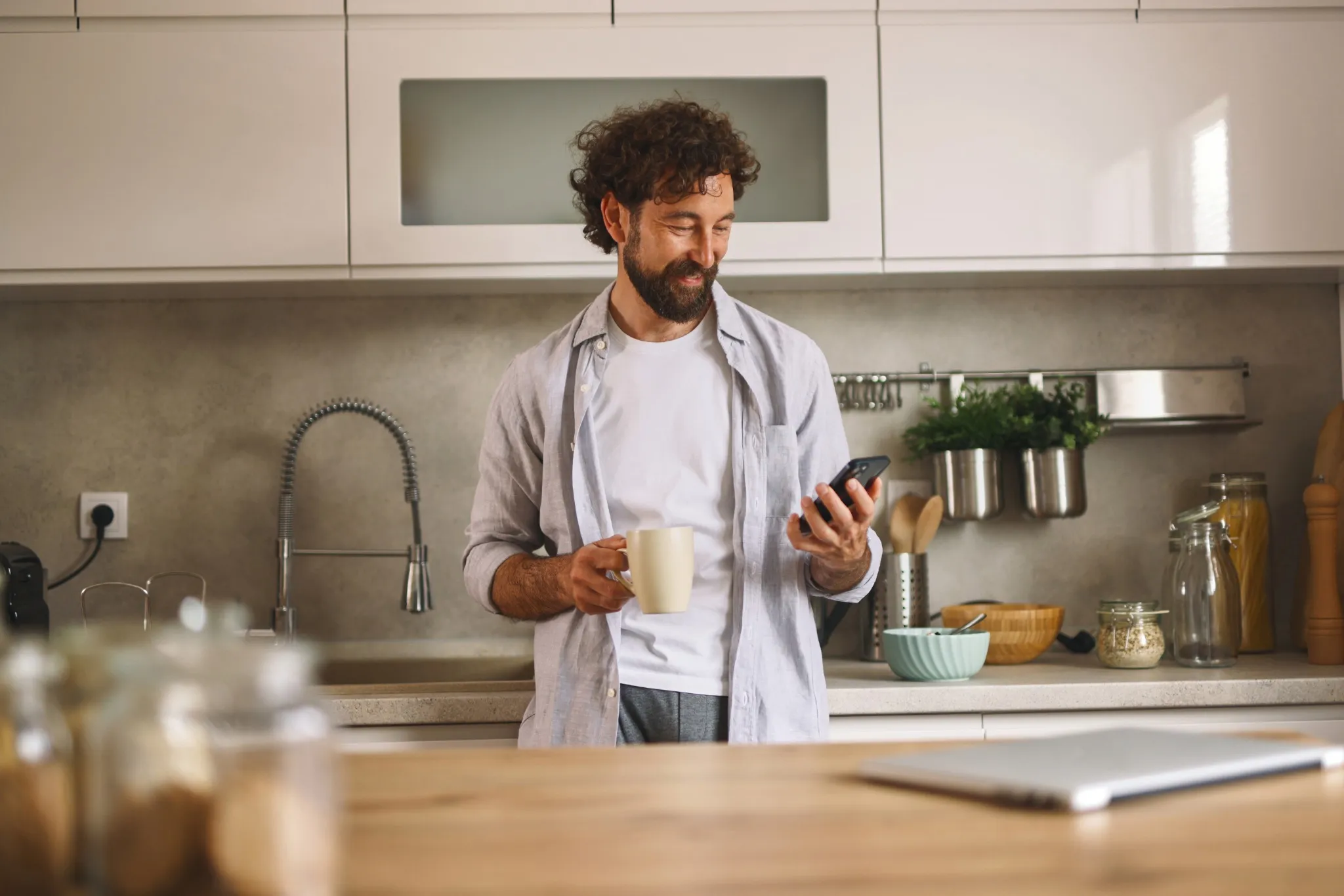 Man standing in his kitchen drinking coffee