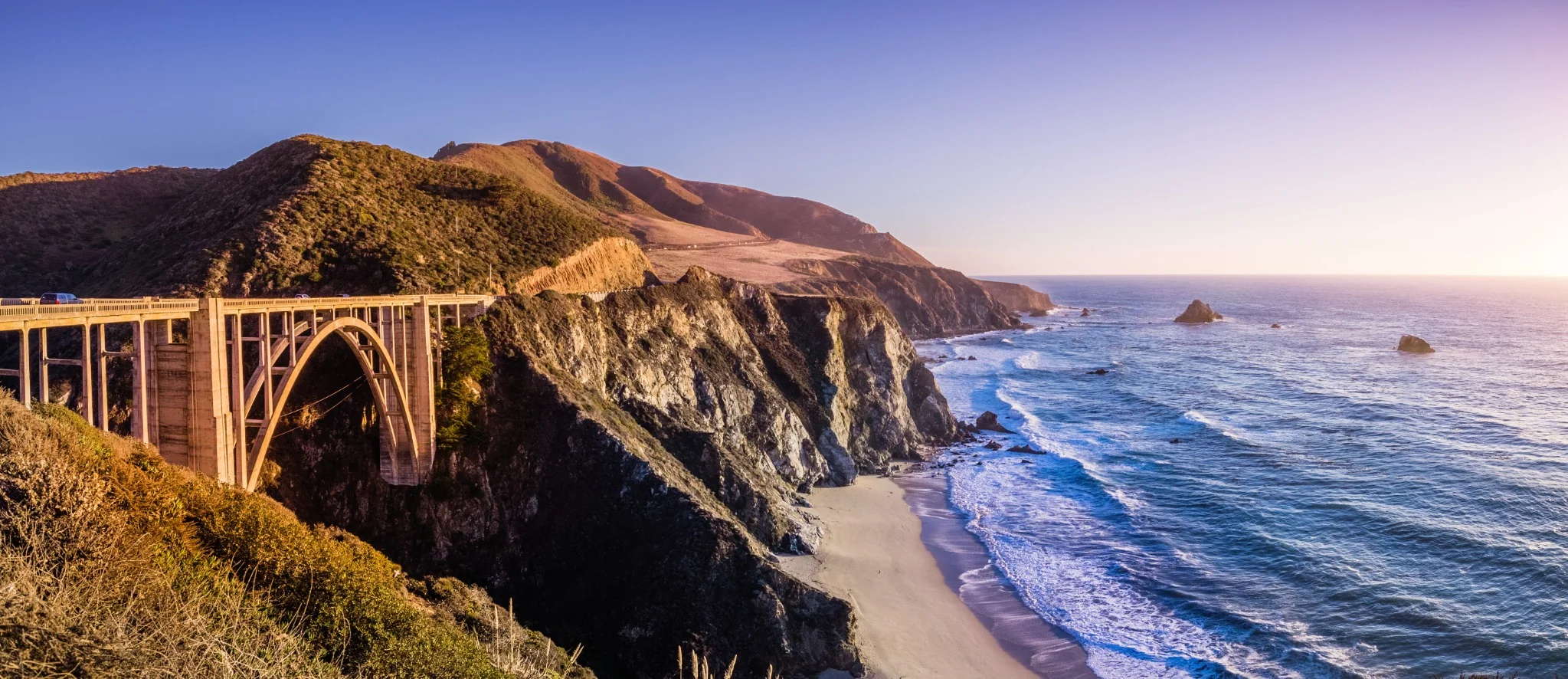 bridge, beach, and rocky cliffs on california coast on sunny day