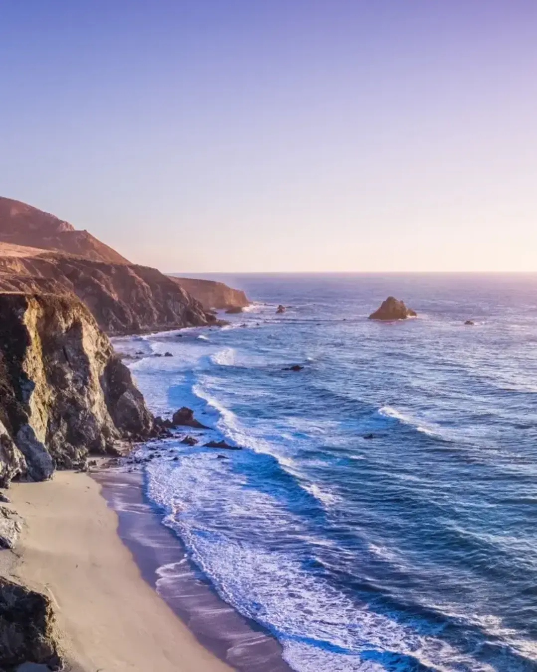 bridge, beach, and rocky cliffs on california coast on sunny day