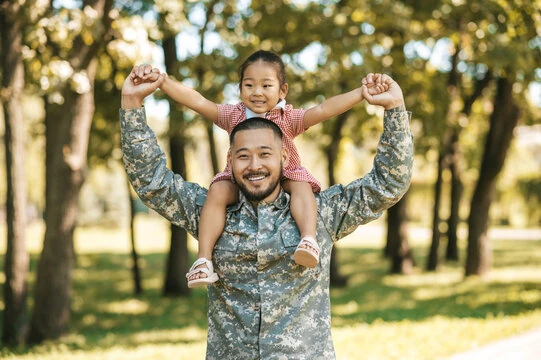 Soldier in uniform with toddler daughter on his shoulders