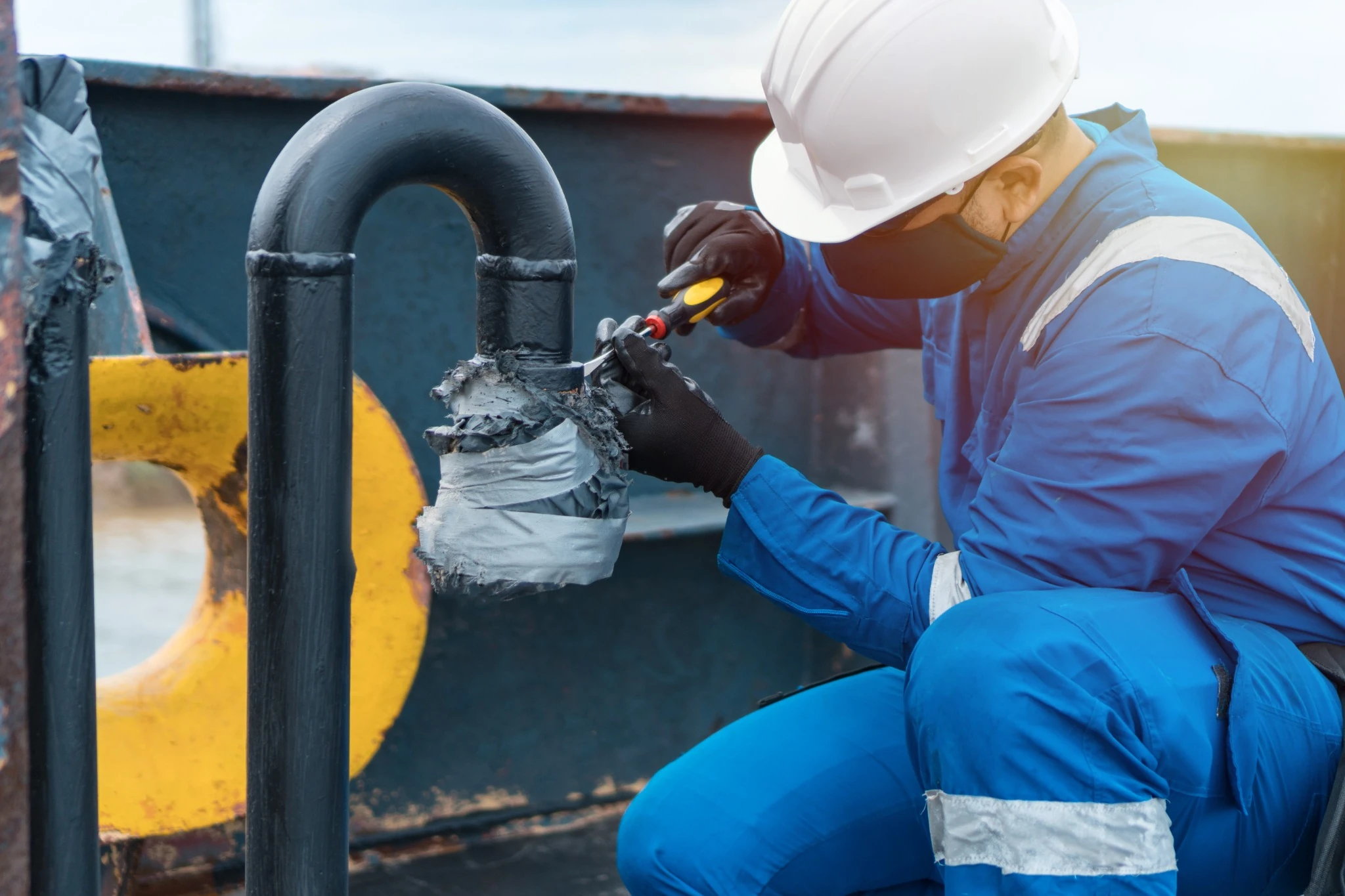 navy ship mechanic working on pipe