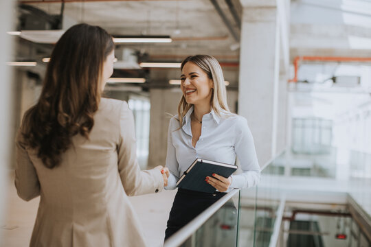 Two young business woman shaking hands