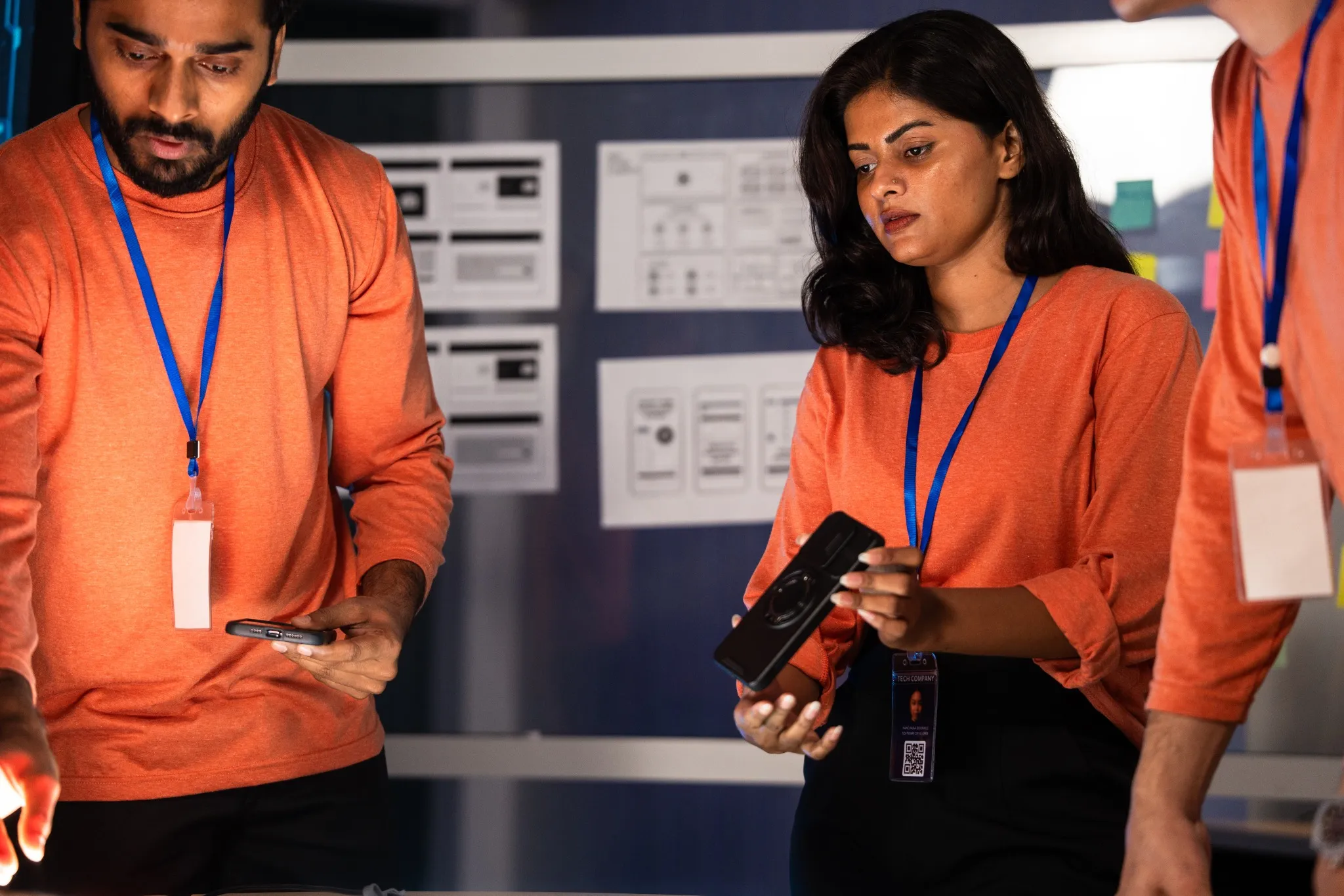 Cybersecurity team working late night in a dark operations center. Collaborating on an urgent data investigation using mobile technology for a digital security analysis.