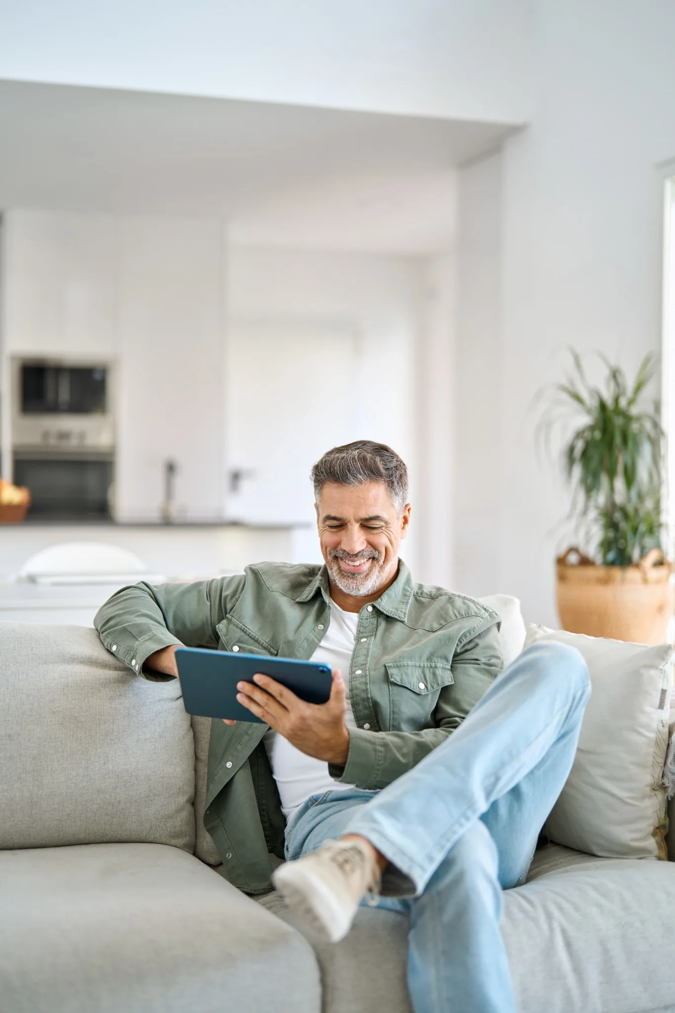 Happy man sitting on couch looking at tablet