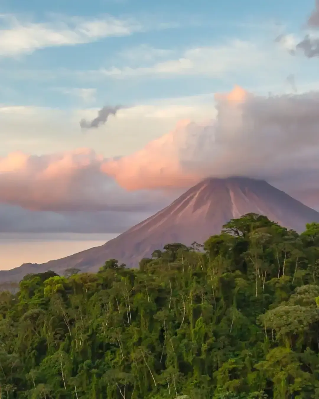 Arenal Volcano at Sunrise in Costa Rica, as the sun reflects on the newly formed clouds
