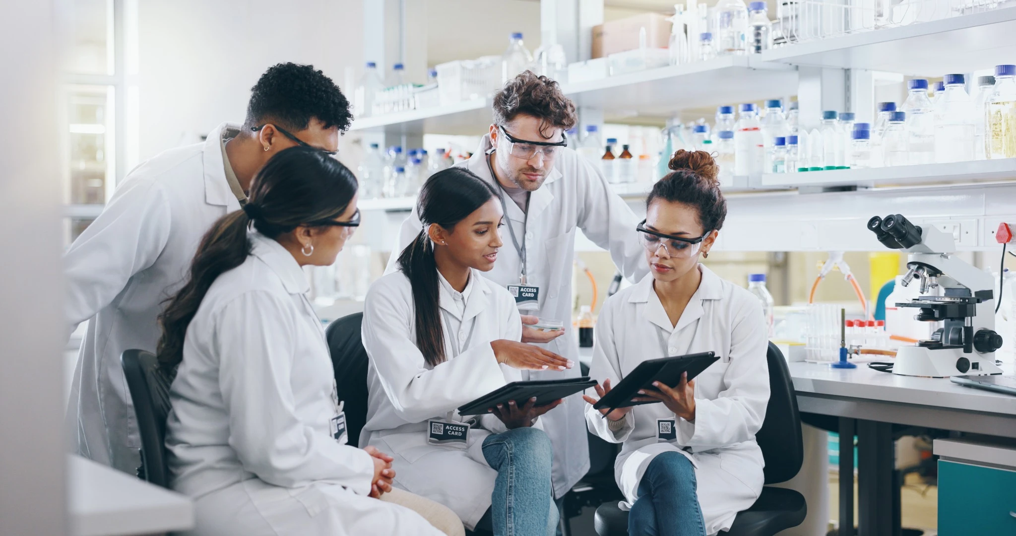 Tablet, science team and people learning for cancer cure, help or medical development in laboratory.