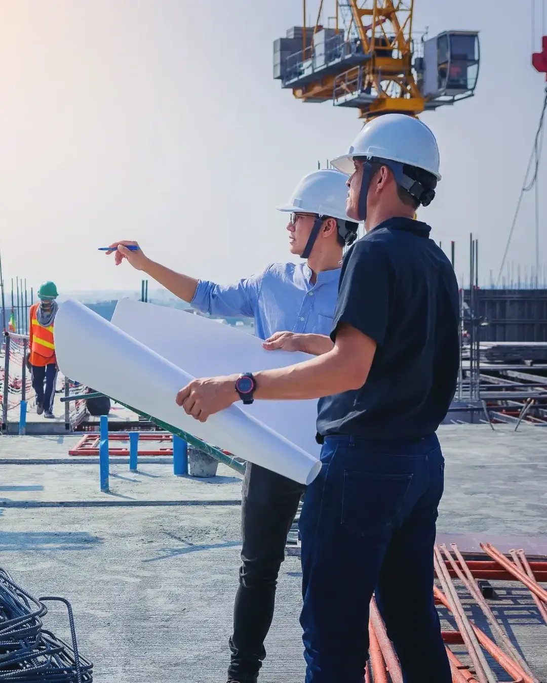 Structural engineer and architect working with blueprints discuss at the outdoors construction site.