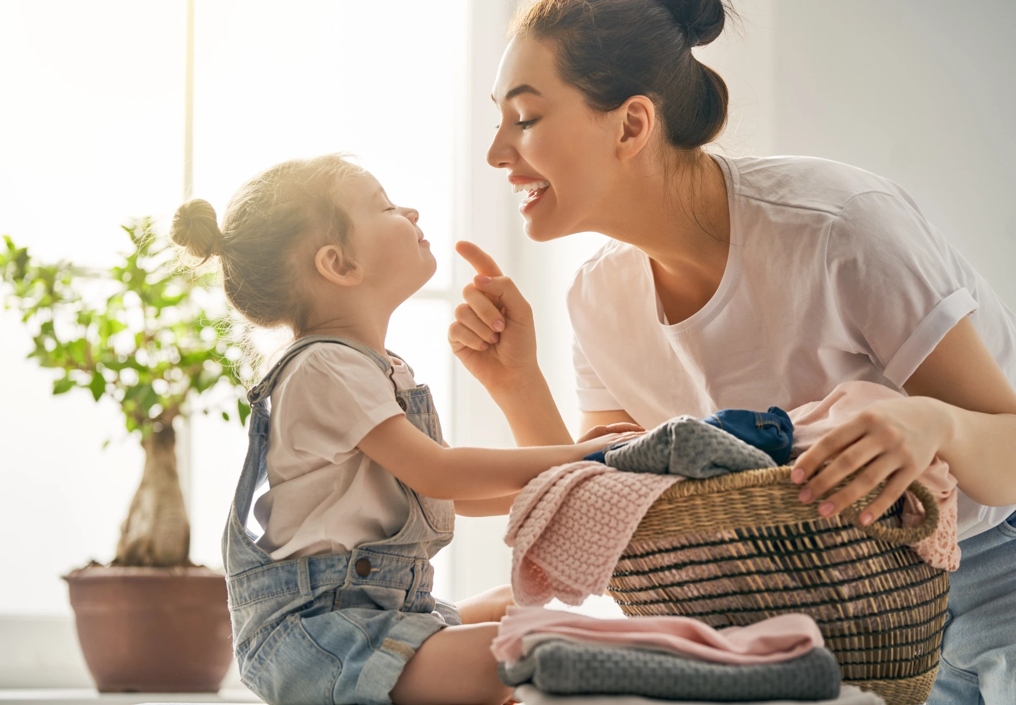 Woman happily doing laundry with toddler