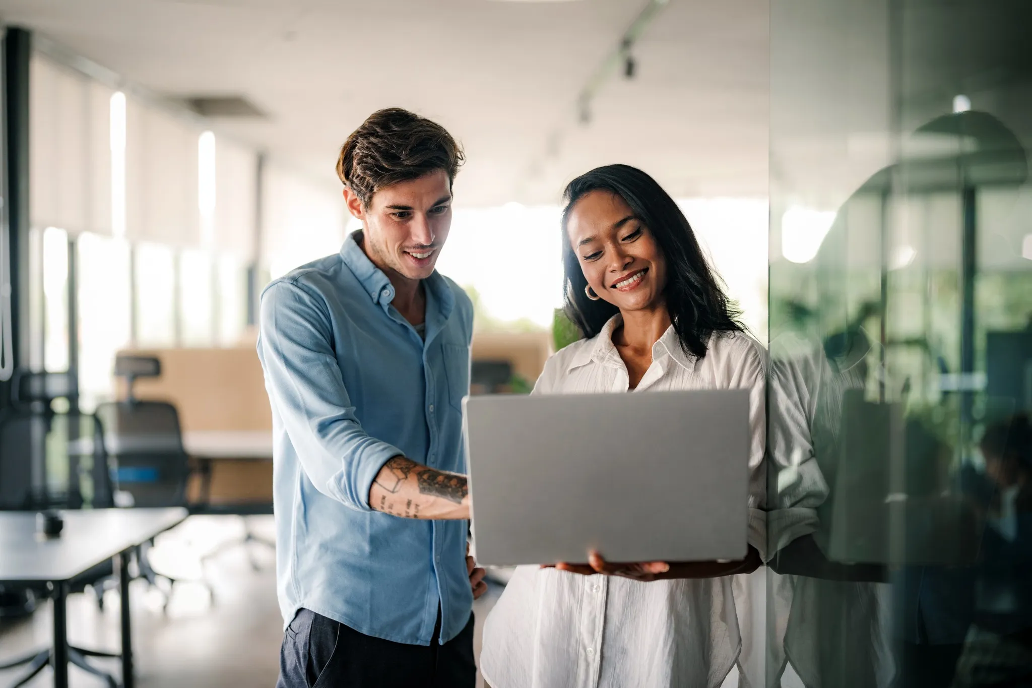 Two happy diverse multiethnic business team people working, talking in corporate office.
