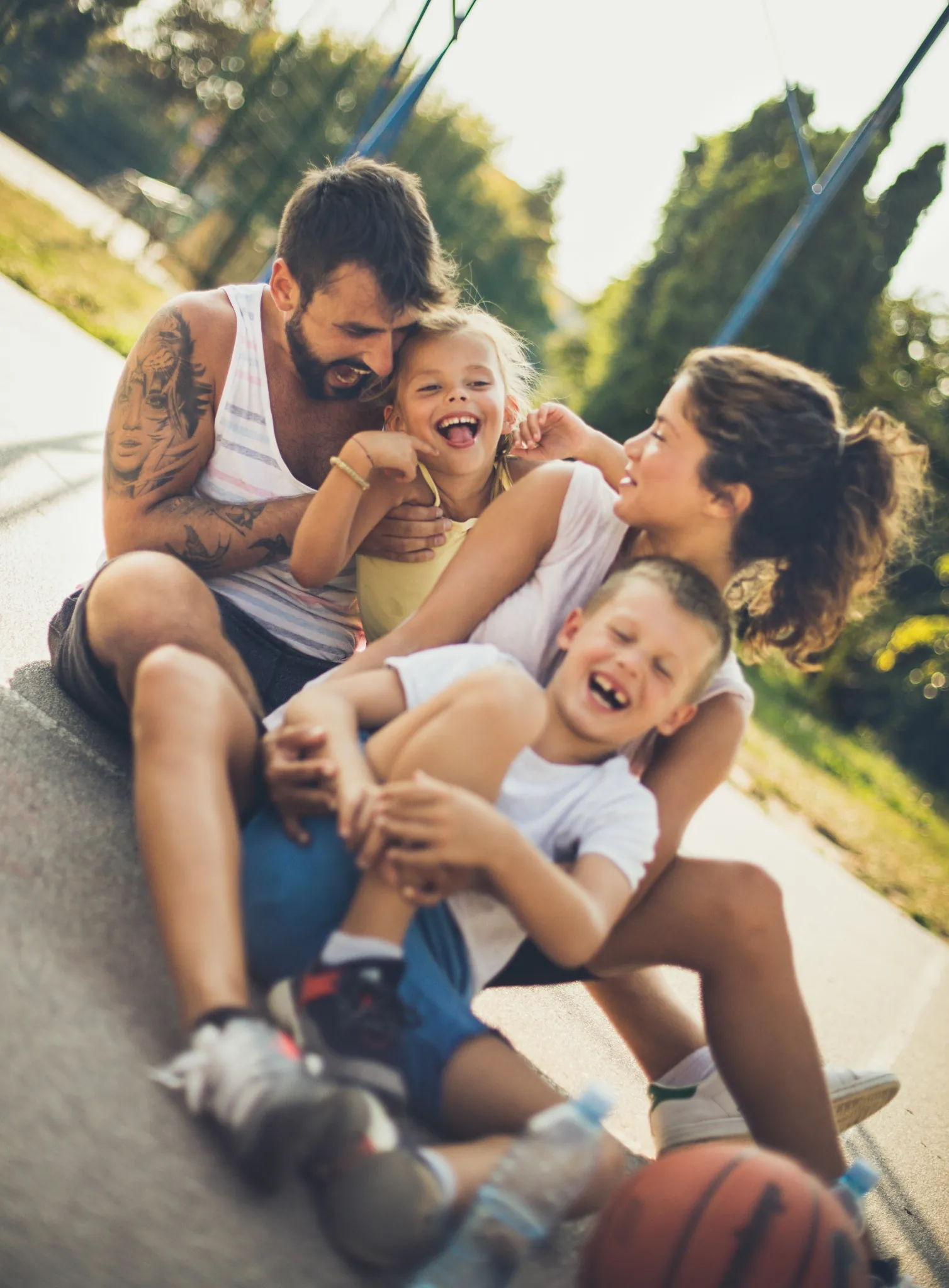 parents with two kids sitting on the ground laughing outside