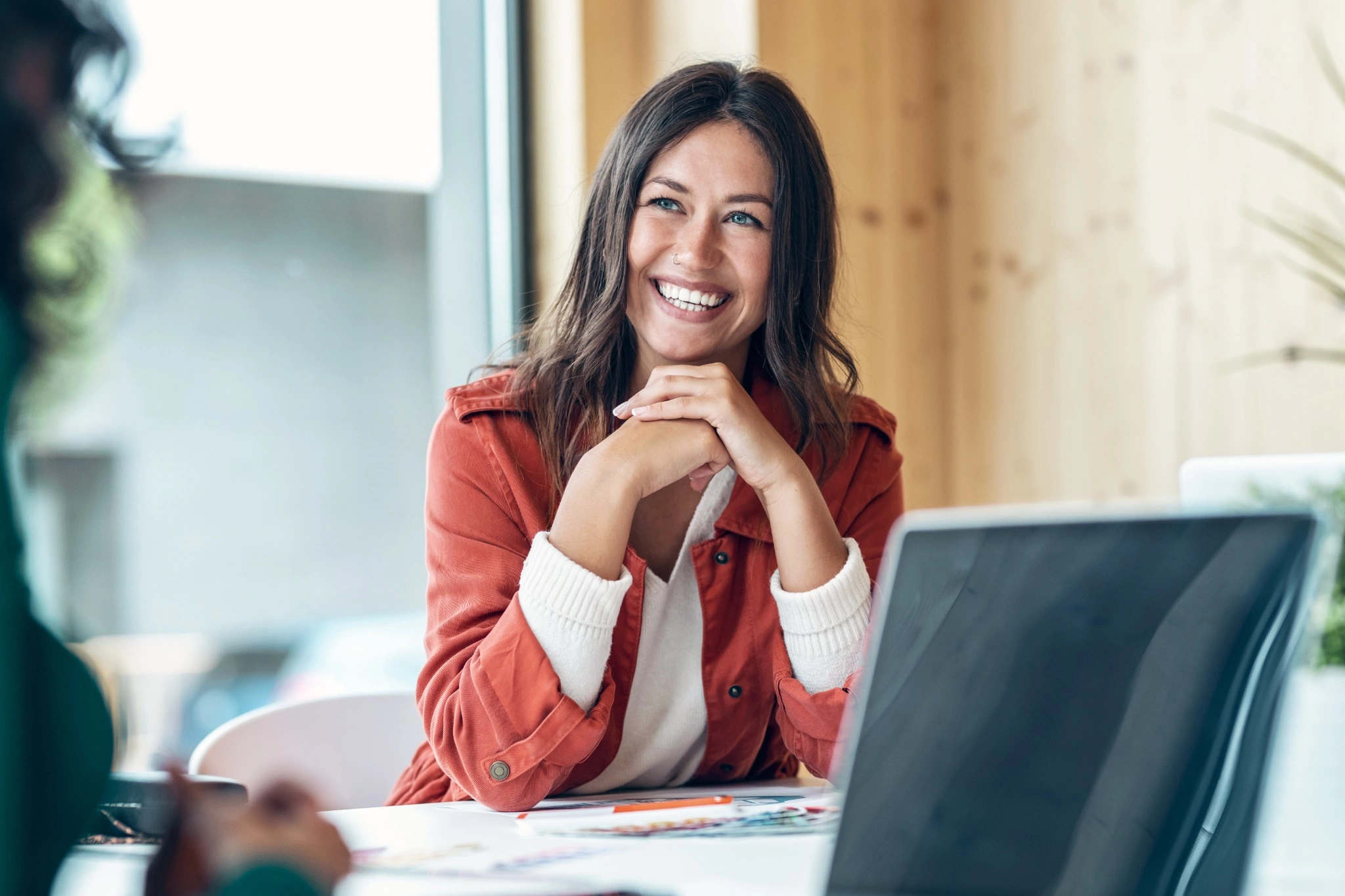 Smiling young business woman listening her partner on coworking space..