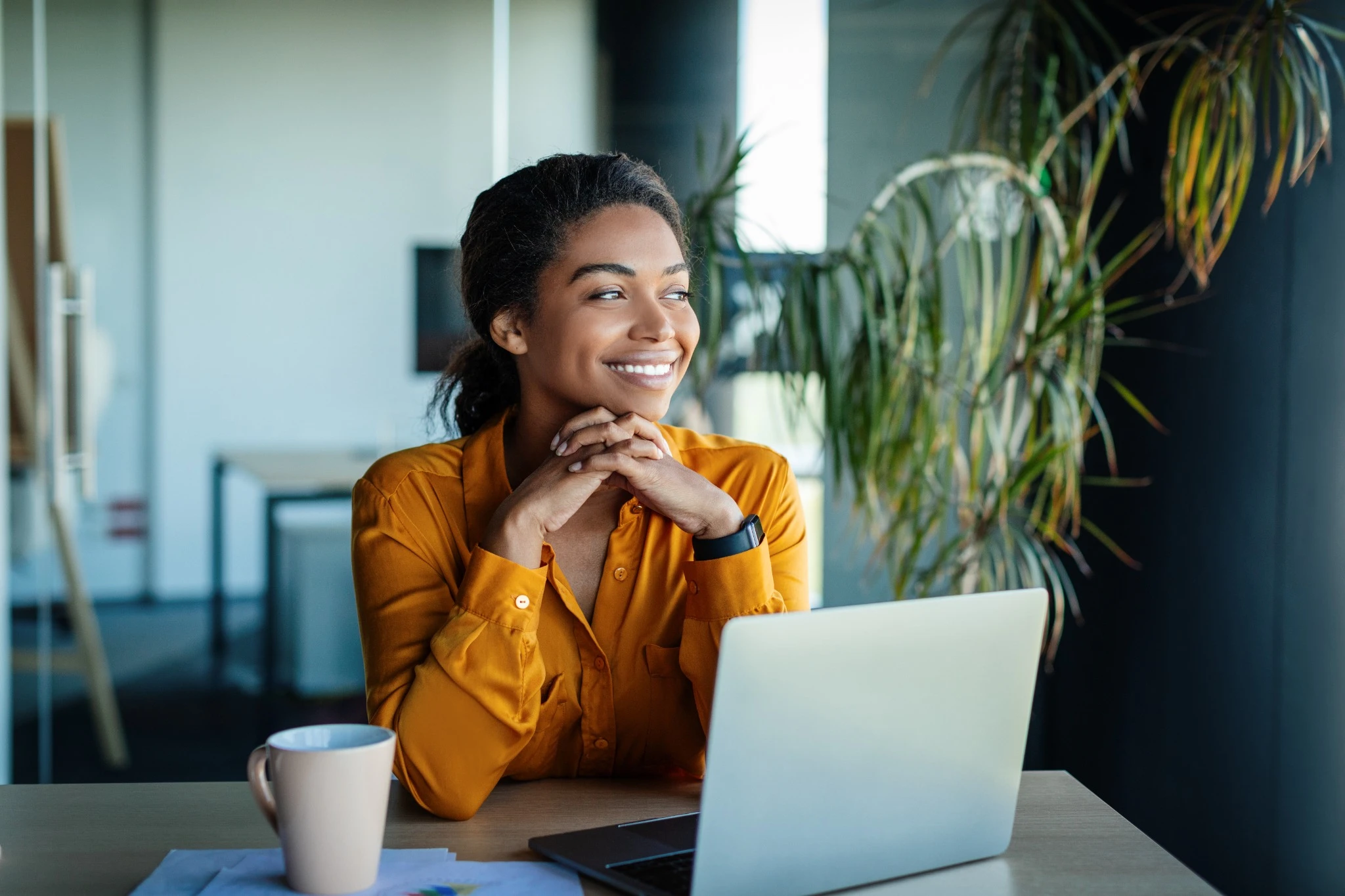 woman at work smiling with laptop and mug