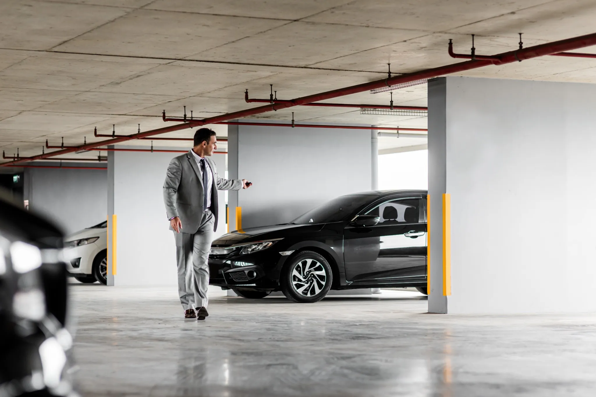 Quick and comfortable. Businessman in grey suit parks his car in underground parking lot. 