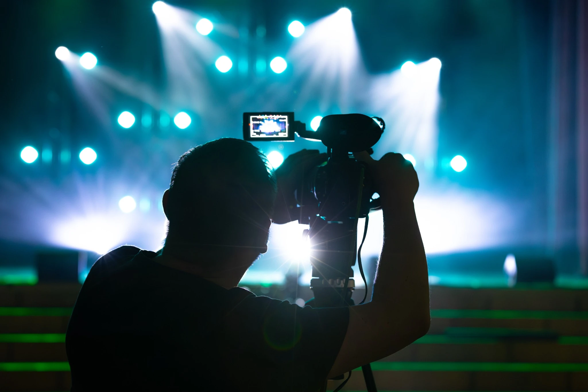 man videoing a performance in a theatre